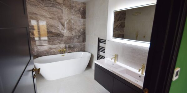 Luxury bathroom with marble walls and modern fitings within an inclusive, bespoke disability-adapted house.