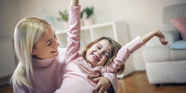 Image of woman with happy young girl in her arms. Representing our work with court appointed guardians