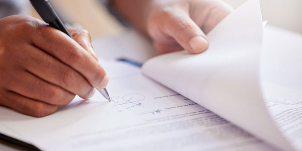 Image of hand signing legal paperwork. Representing support partners for adapted home projects.