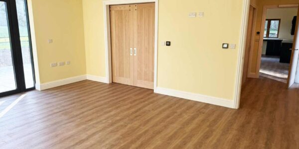 Bright and airy bedroom with en-suite wheelchair accessible wet room. Oak doors and flooring compliments pale yellow walls with lowered sockets and Smart Home Automation controls.