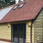 Accessible annexe building with solar panels and heat pump. Shown with wood cladding before it was darkened to blend with its heritage setting in Kent.