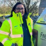 Photo of Sam Mohabir in a high-vis jacket standing next to a an with the Freedom living Solution logo